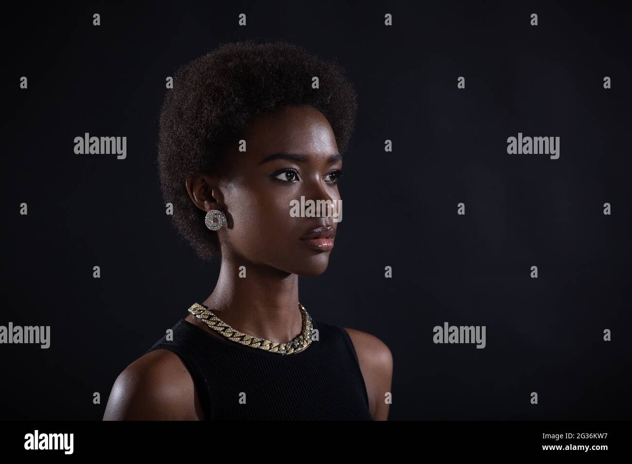 Gros plan demi-tour portrait de femme afro-américaine avec une coiffure afro-américaine sur fond noir de studio. Banque D'Images