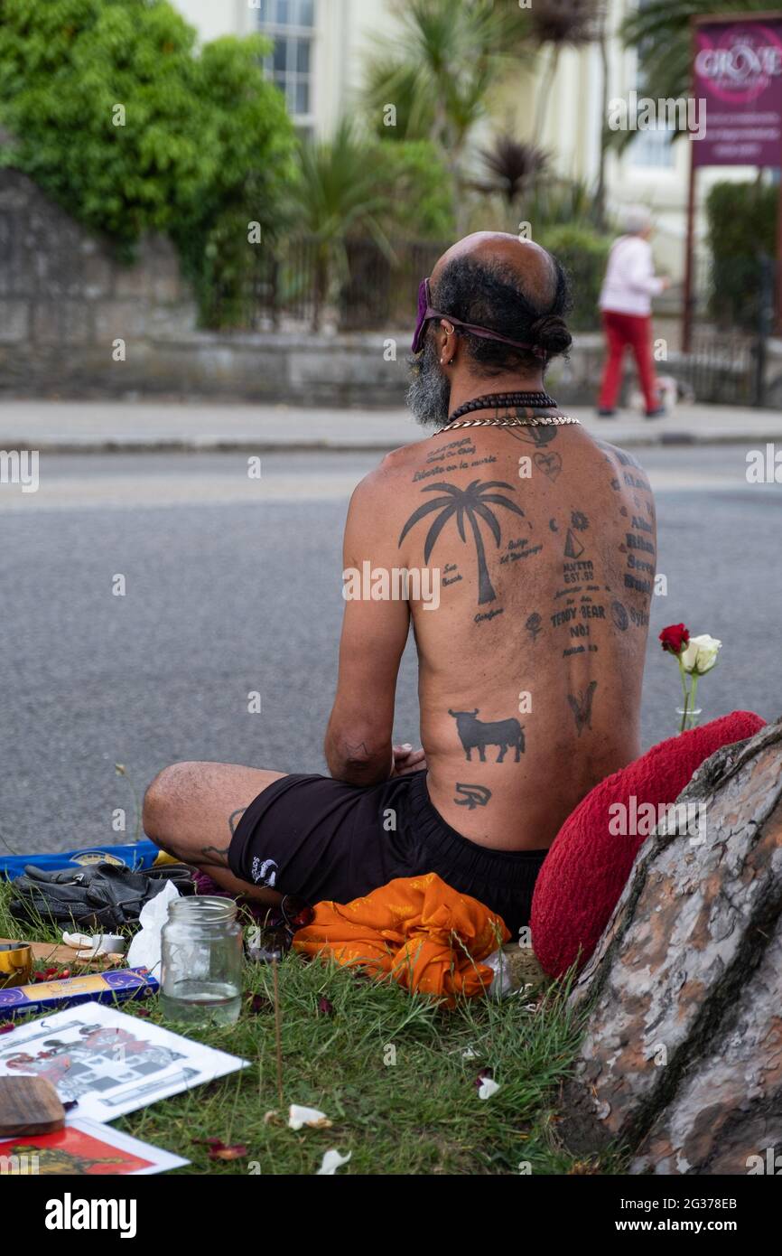 Le protestataire contre le changement climatique de Falmouth a été tatoué lors du sommet du G7 à Cornwall.Assis sous un arbre entouré de fleurs et de bits. Banque D'Images