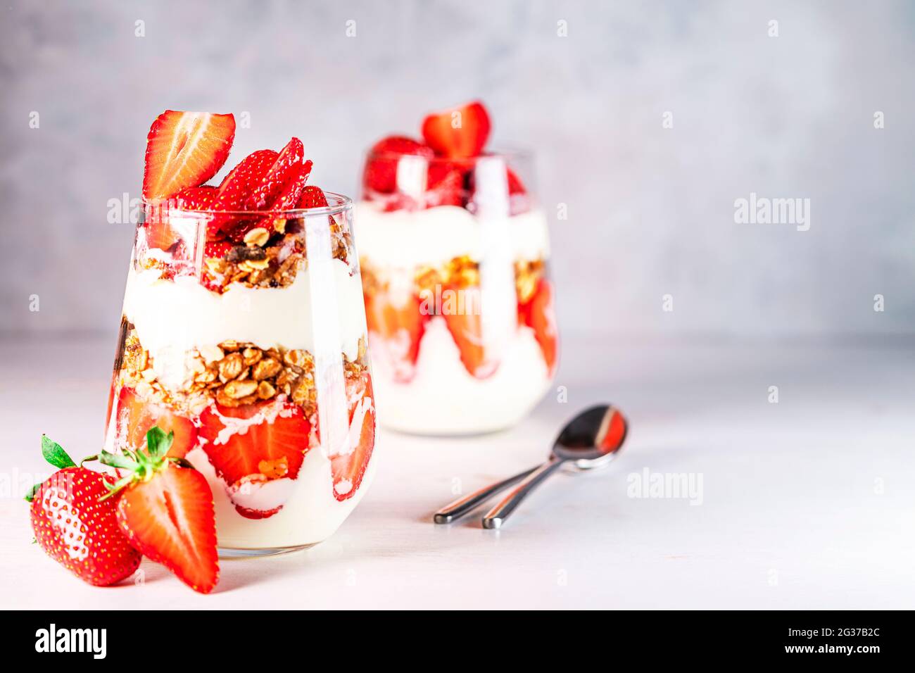 Petit déjeuner sain composé de parfaits aux fraises, de yaourts et de muesli frais en verres. Banque D'Images