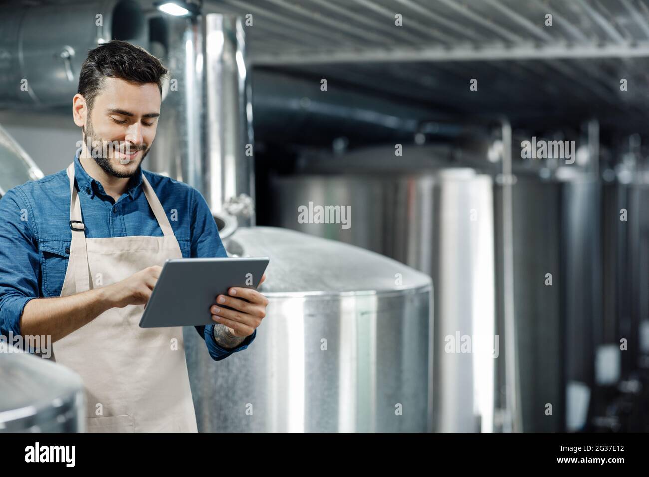 Un jeune homme travaille à l'usine de bière. Brasseur, équipement industriel et dispositif numérique intelligent moderne à la brasserie Banque D'Images