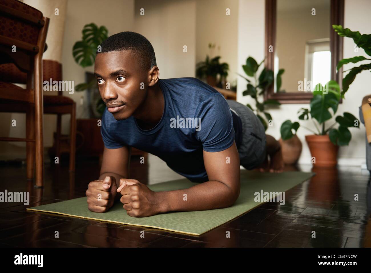 L'homme africain faisant l'avant-bras a planche pendant un yoga à la maison Banque D'Images