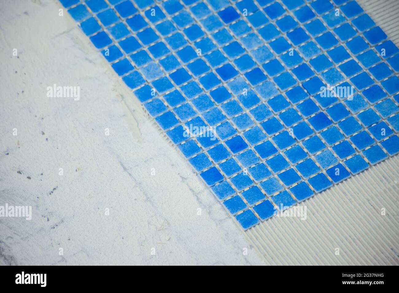 Employé posant des carreaux dans la piscine. Travaux de réparation de piscine. Banque D'Images