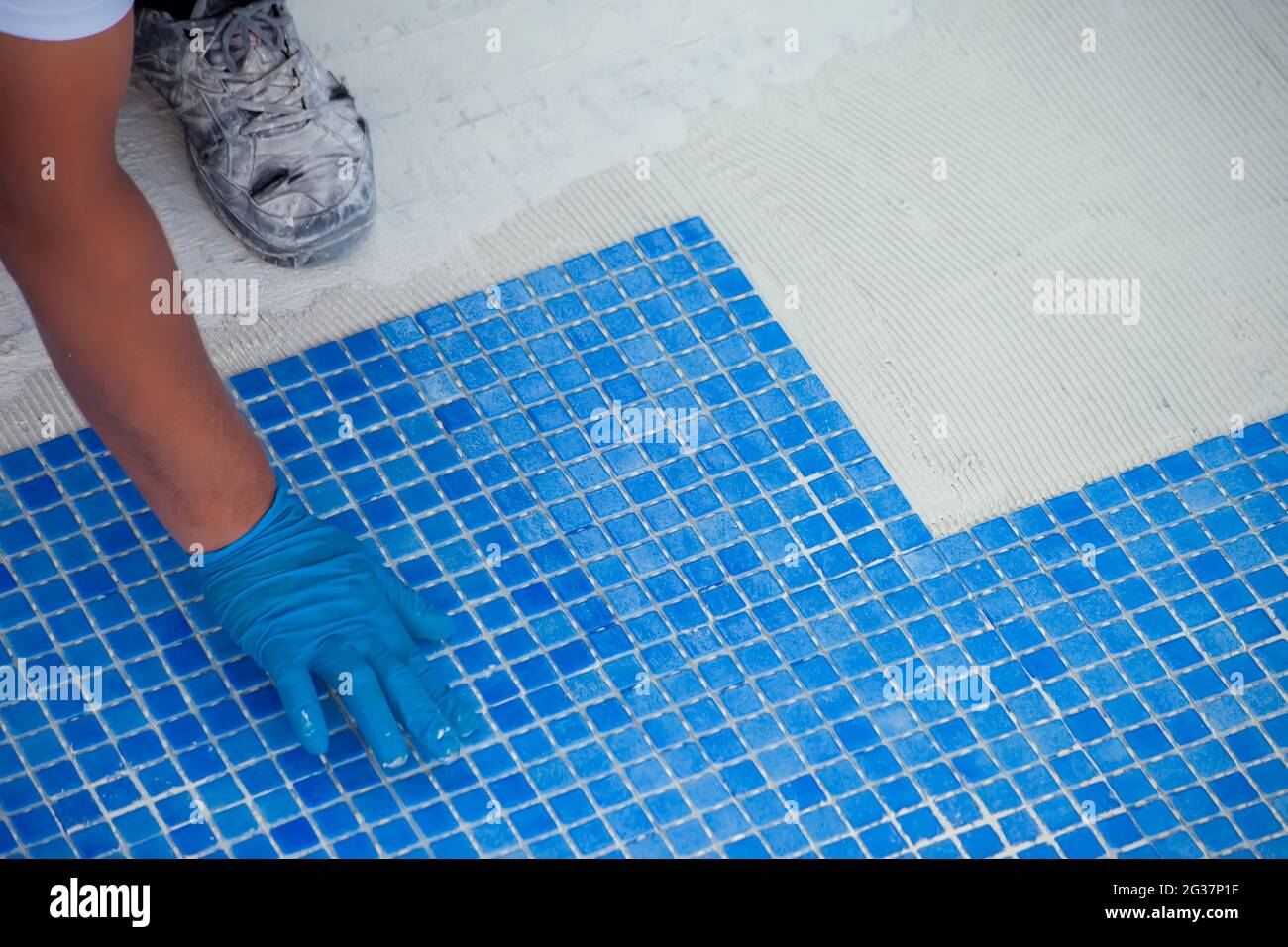 Employé posant des carreaux dans la piscine. Travaux de réparation de piscine. Banque D'Images