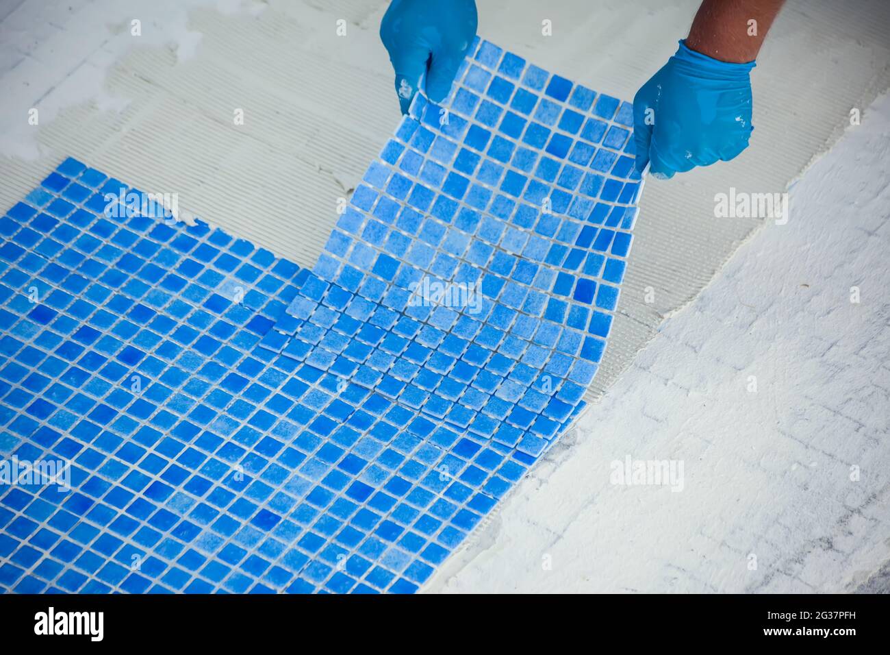 Employé posant des carreaux dans la piscine. Travaux de réparation de piscine. Banque D'Images