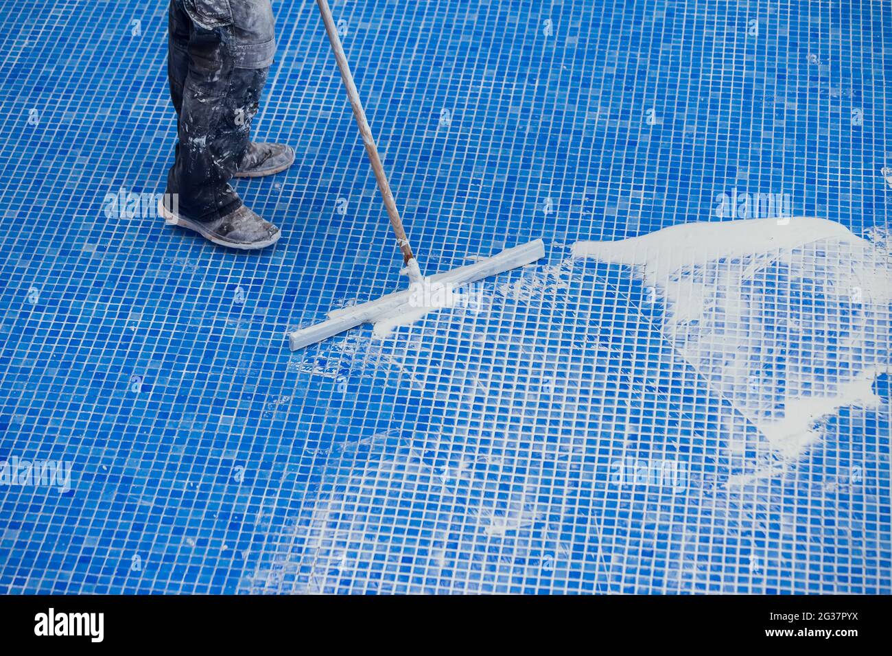 L'employé qui couvre les noms de la tuile dans la piscine. Travaux de réparation de piscine Banque D'Images