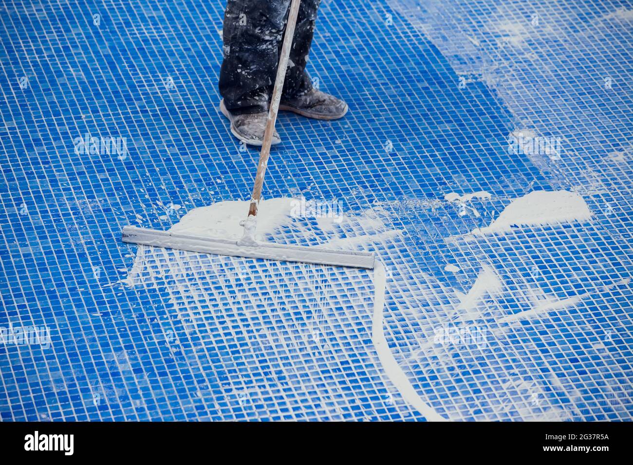 L'employé qui couvre les noms de la tuile dans la piscine. Travaux de réparation de piscine Banque D'Images