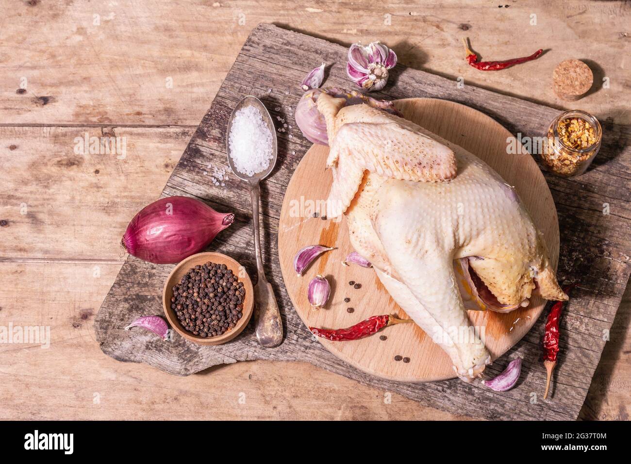 Carcasse brute de poulet entier pour un mode de vie alimentaire sain. Oiseau de ferme à aire libre avec oignon rouge, gousses d'ail, épices et sel de mer. Une lumière dure tendance, d Banque D'Images
