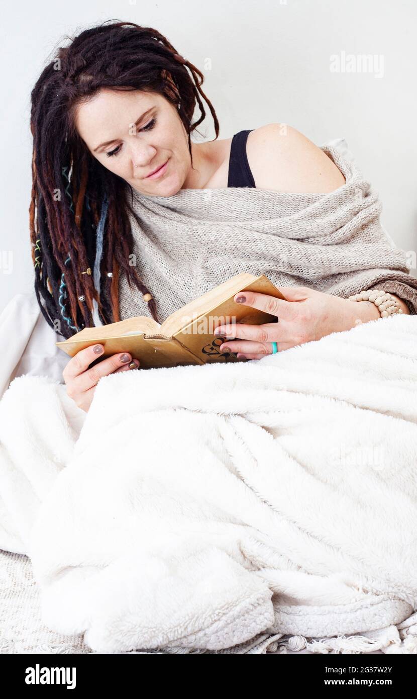 femme se détendant à la maison, confortable dans une couverture, lecture Banque D'Images