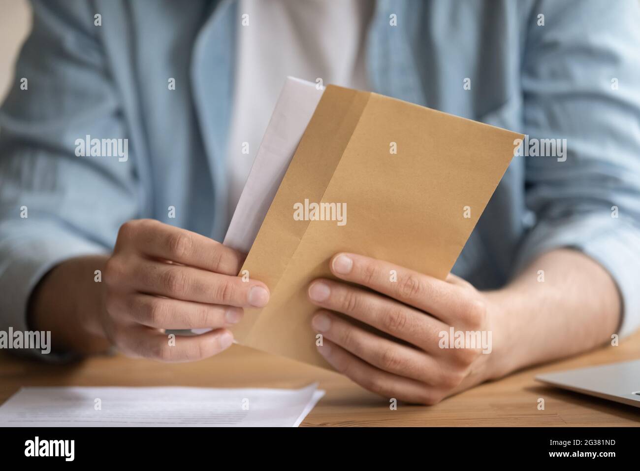 Gros plan jeune homme ouvrant l'enveloppe, se sentant curieux. Banque D'Images