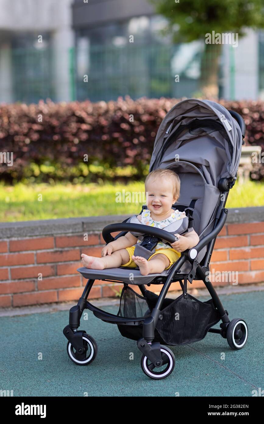Adorable Jeune Fille Ou Garcon Caucasien Assis Dans Une Poussette Dans Le Parc D Ete A La Chaude Journee Ensoleillee Beau Bebe Avec Les Cheveux Blonds Et Les Yeux Bleus Regardant Photo Stock