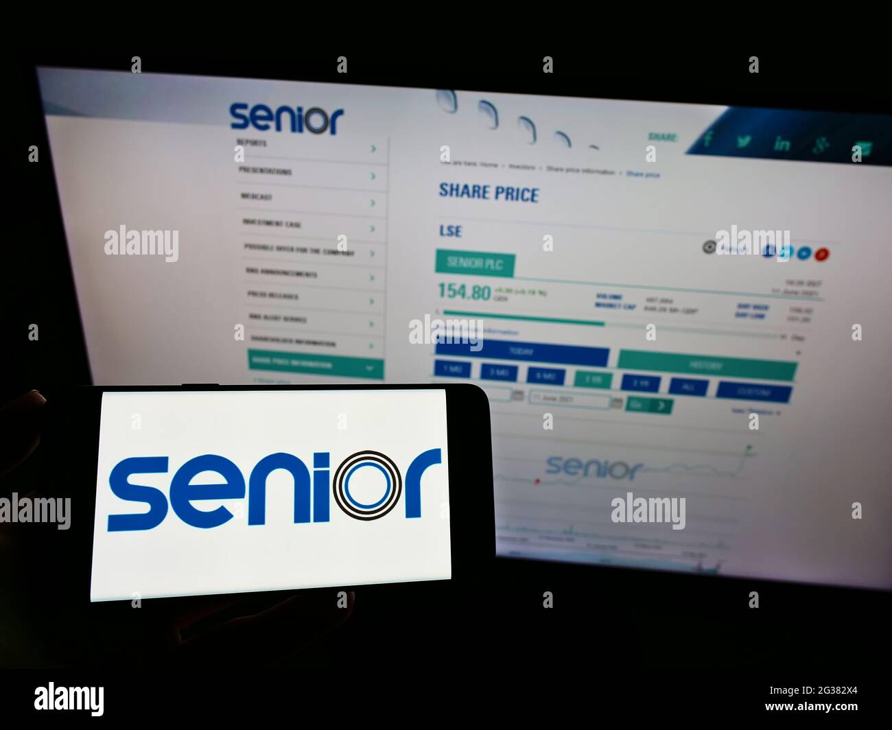 Personne détenant un smartphone avec le logo de la société de fabrication britannique Senior plc à l'écran devant le site Web. Mise au point sur l'affichage du téléphone. Banque D'Images
