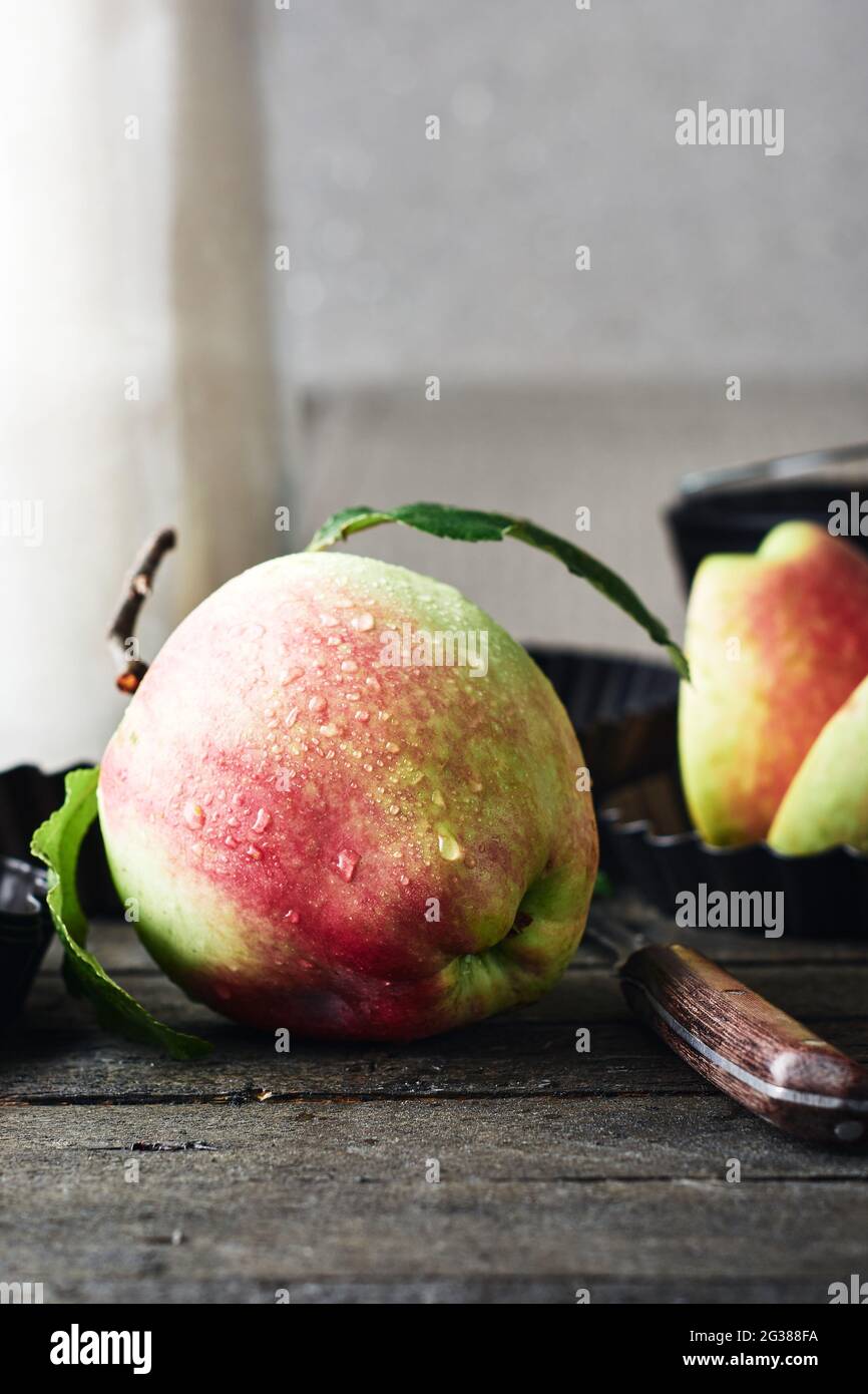 Pomme rouge avec gouttes d'eau sur une table de cuisine en bois. Banque D'Images