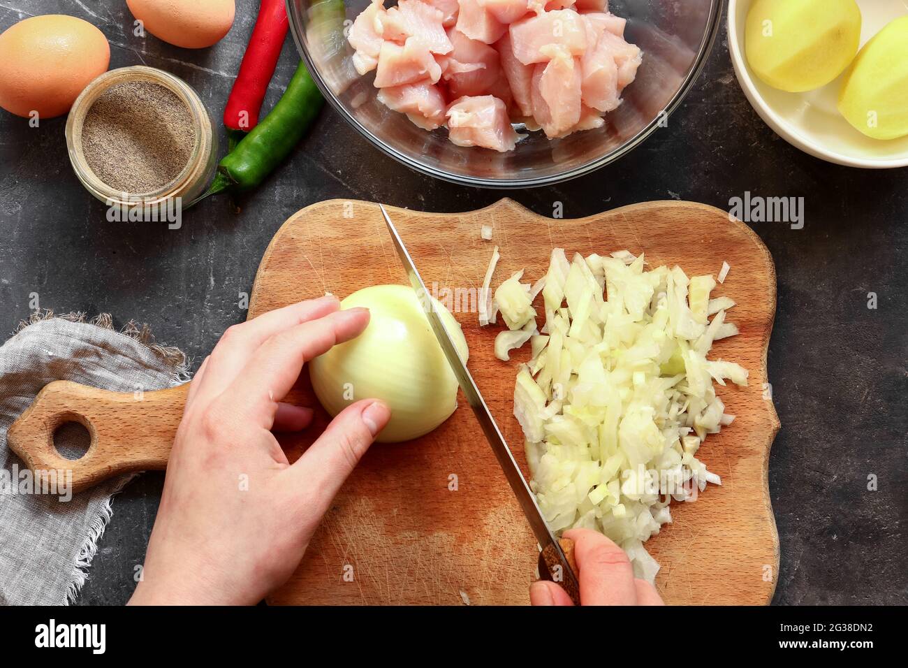 Oignon tranché sur une planche de bois. Préparation étape par étape de viande hachée pour boulettes de poulet. Vue de dessus. Processus de cuisson dans la cuisine. Recette. Banque D'Images