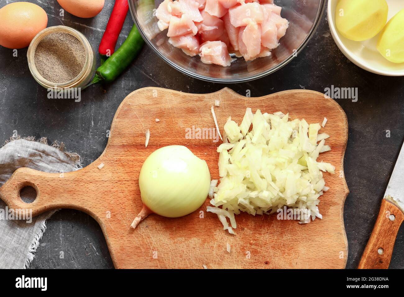 Oignon tranché sur une planche de bois. Préparation étape par étape de viande hachée pour boulettes de poulet. Vue de dessus. Processus de cuisson dans la cuisine. Recette. Banque D'Images