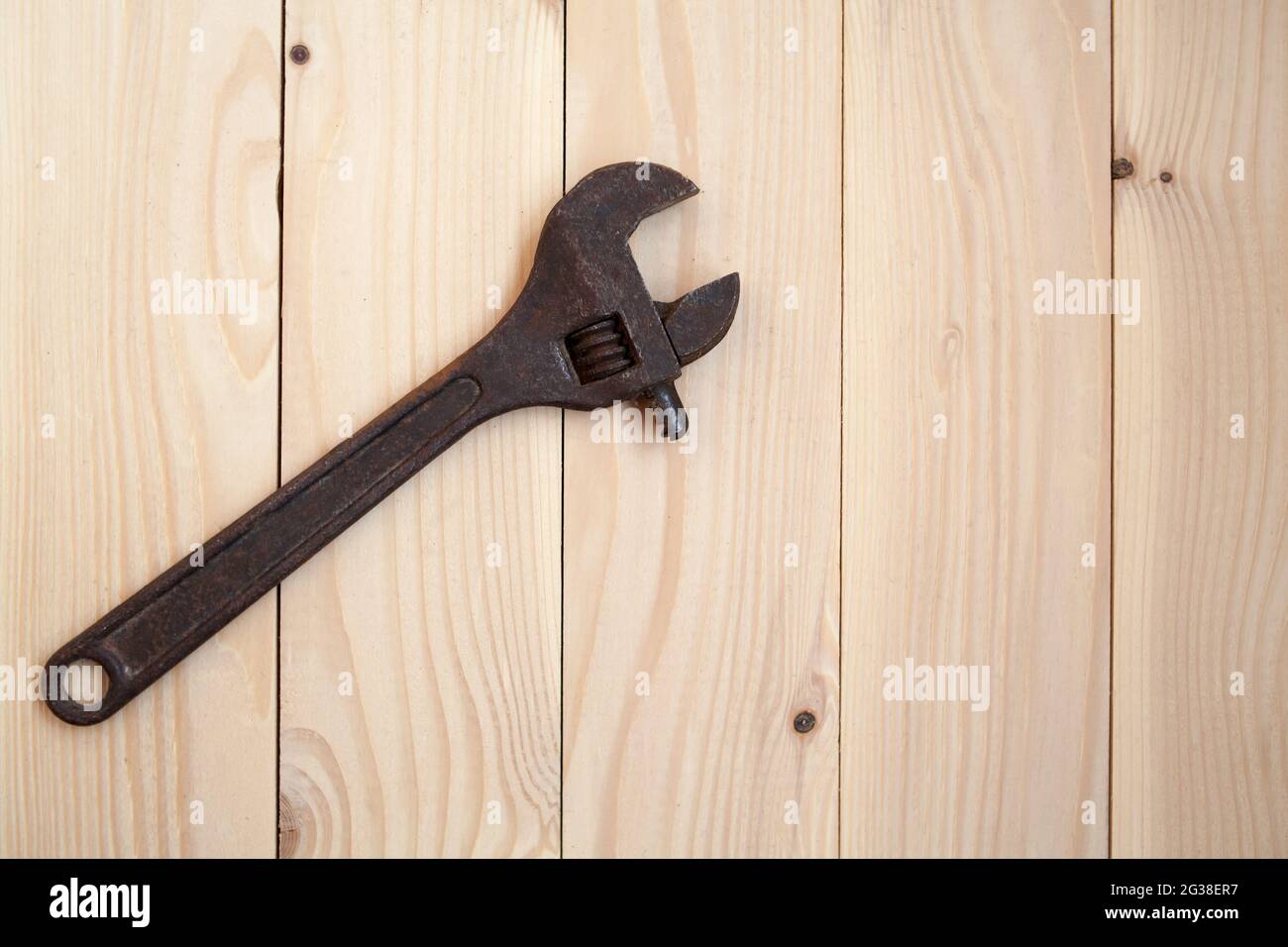 Ancienne clé à molette rouillée sur fond en bois clair. Concept de travail. Banque D'Images