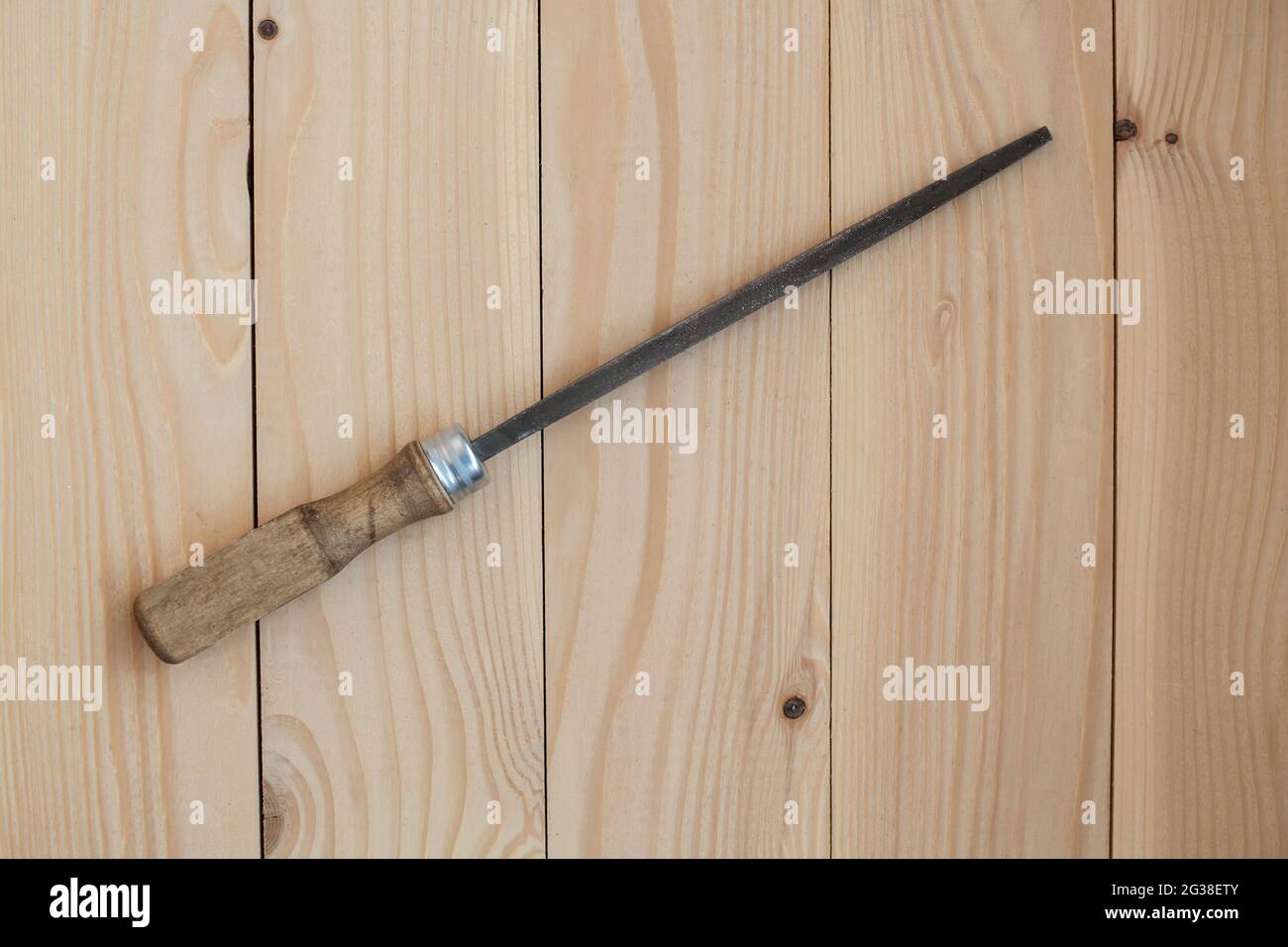 Une lime avec une poignée en bois pour le traitement du métal sur un fond en bois clair. Banque D'Images