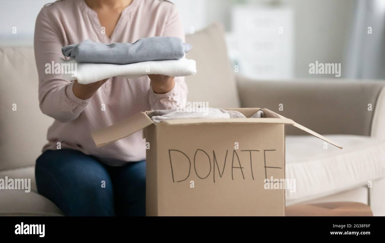 Femme donnant des vêtements, emballage de la boîte de don à la maison Banque D'Images