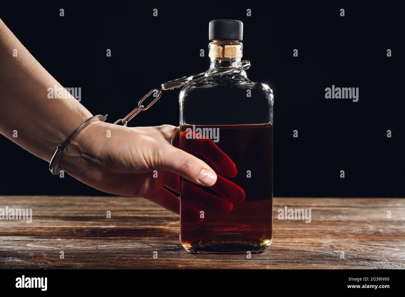 Femme menottée à une bouteille de whisky. Concept d'alcoolisme Banque D'Images