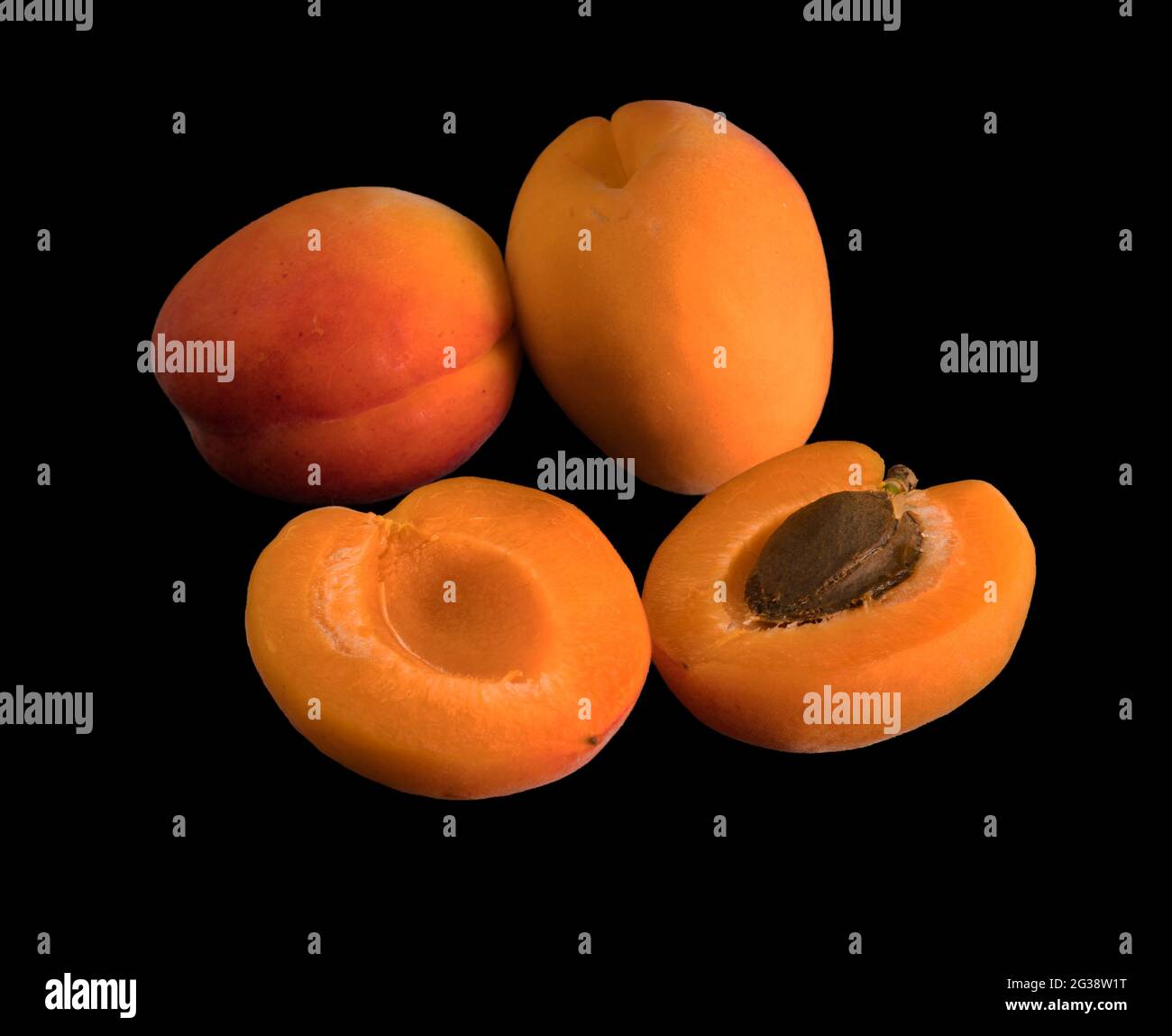 Un bouquet de fruits Apricot mûrs, deux entiers et un divisé par deux, sur fond noir, isolés Banque D'Images