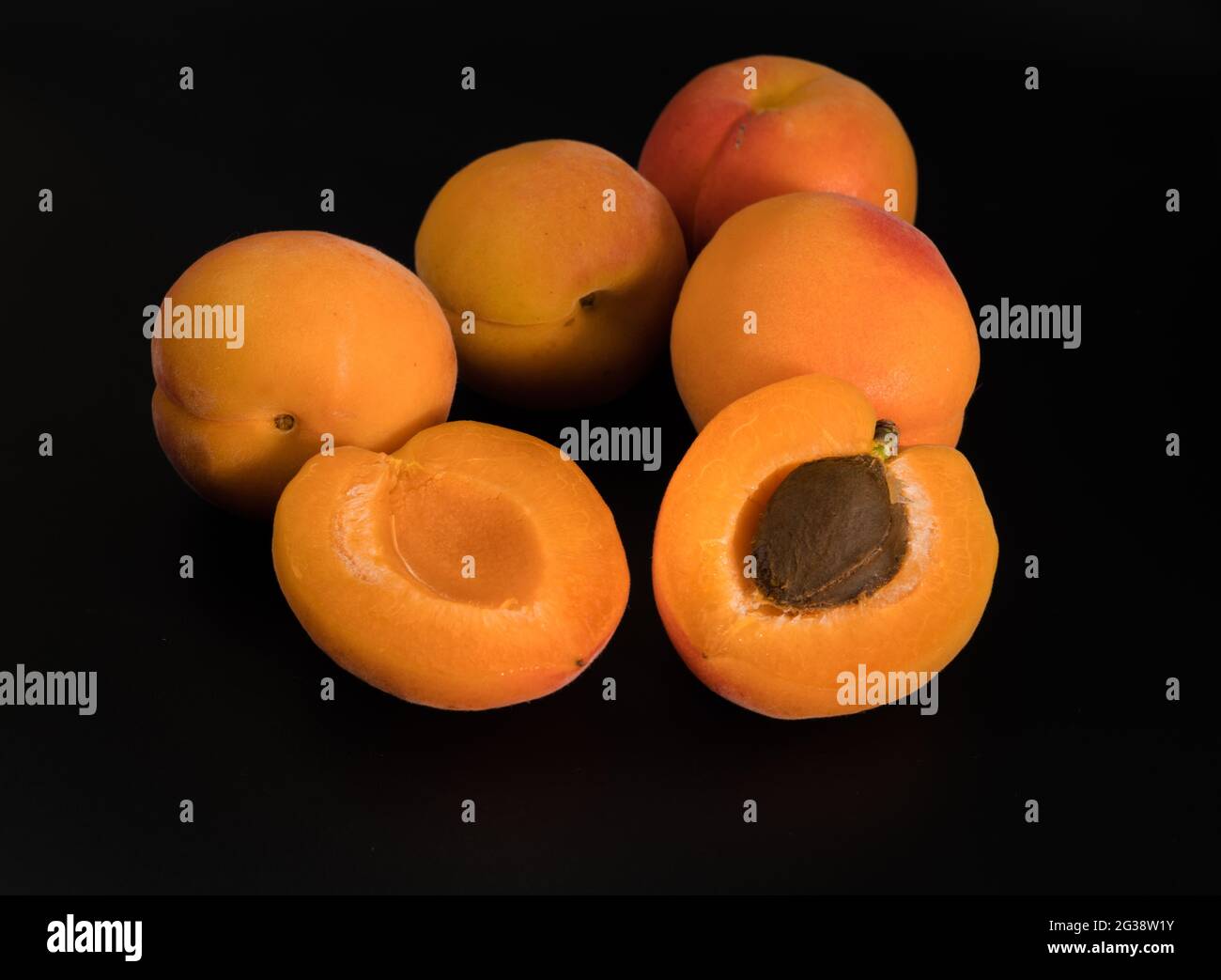 Un bouquet de fruits Apricot mûrs, entiers et en tranches, sur un fond noir en isolement Banque D'Images