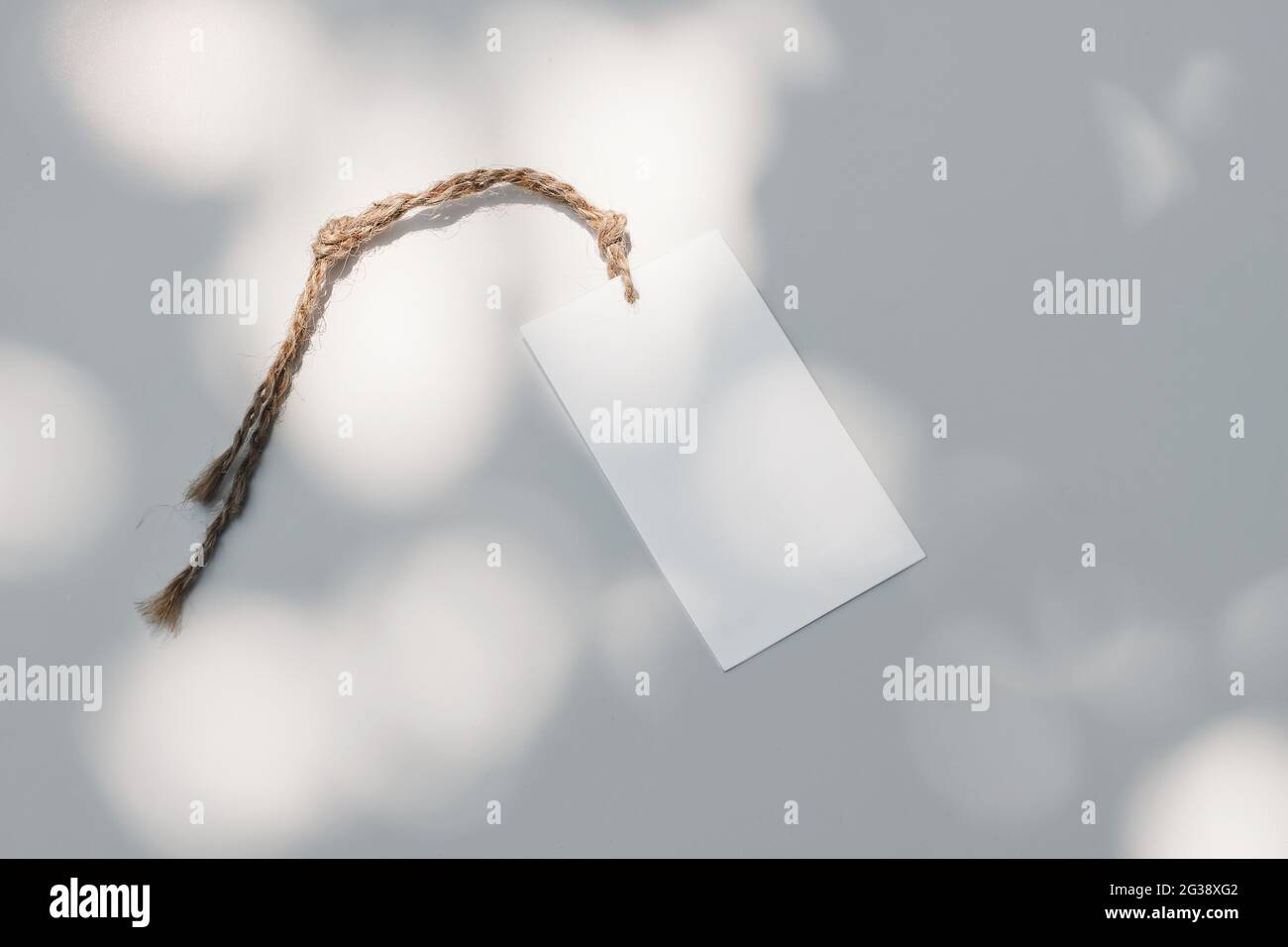 Gros plan de l'étiquette-cadeau en papier, étiquette de prix avec une corde de trope en sisal sur fond blanc de table au soleil. Image de marque. Soldes d'été Banque D'Images