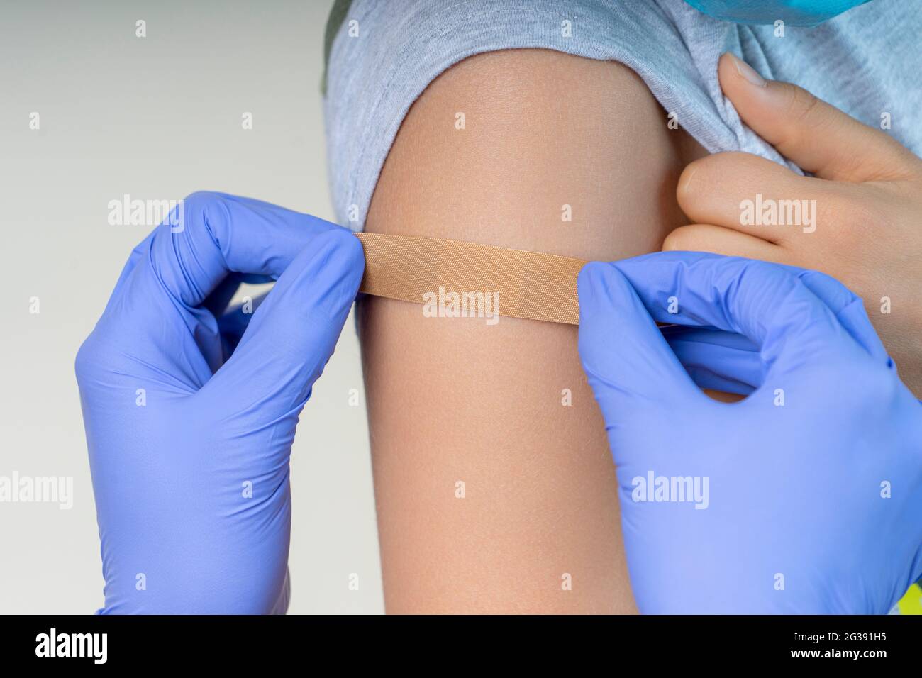 Infirmière dans des gants de protection en caoutchouc mettant le pansement  adhésif sur le bras du jeune garçon après la vaccination. Injection vaccin  covid, concept de santé Photo Stock - Alamy