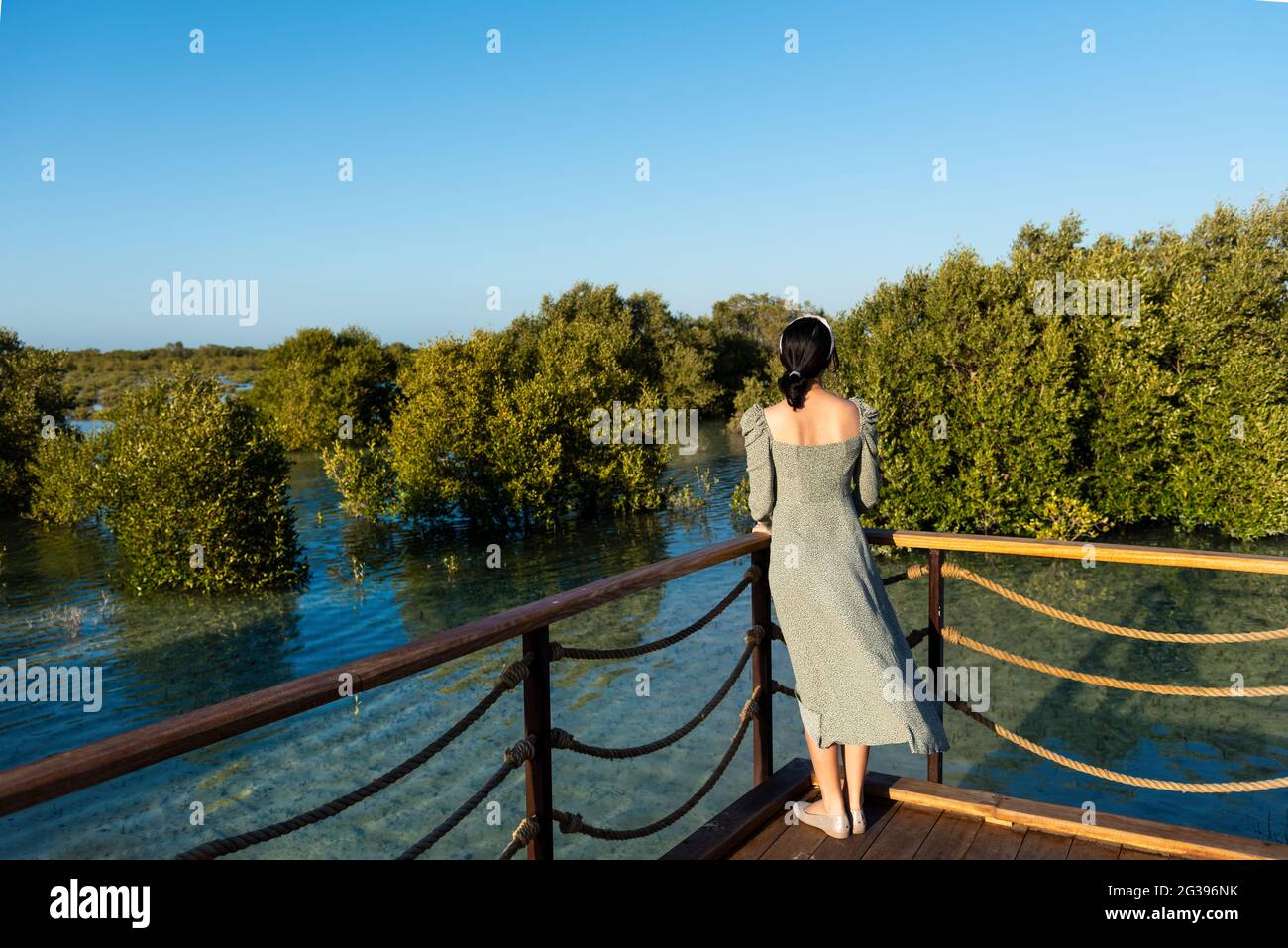 Femme visitant la mangrove promenade du bord de mer parc public dans l'île de Jubail Abu Dhabi, la capitale des Émirats arabes Unis Banque D'Images
