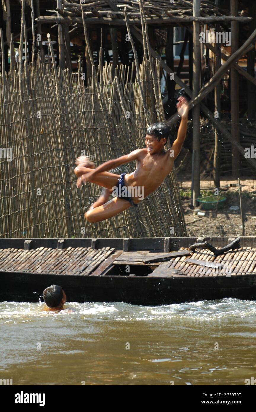 Un garçon saute dans l'eau à partir d'un bateau, dans le village flottant, dans la forêt inondée de Kompong Phhluk, à Siem Reap, au Cambodge. 27 décembre 2006. Banque D'Images