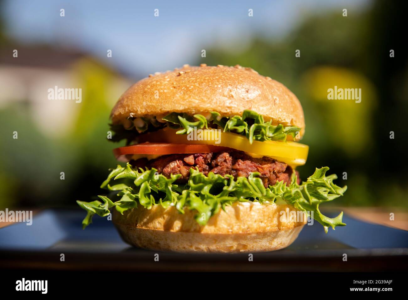 Hamburger végétarien aux haricots verts sur une assiette noire à l'extérieur Banque D'Images