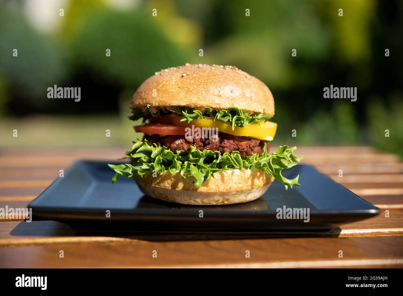 Hamburger végétarien aux haricots verts sur une assiette noire à l'extérieur Banque D'Images