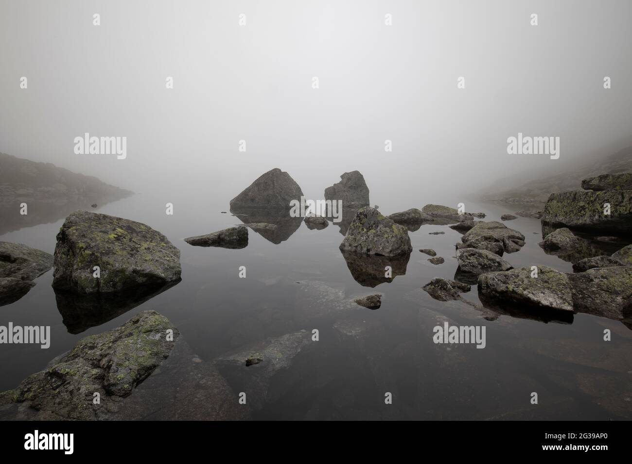 Matin brumeux à un lac dans les montagnes Tatra, rochers se reflétant dans l'eau Banque D'Images