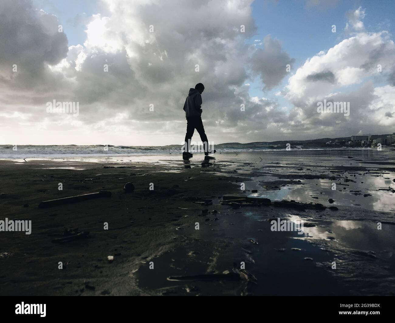 Un garçon solitaire marche sur la plage Banque D'Images