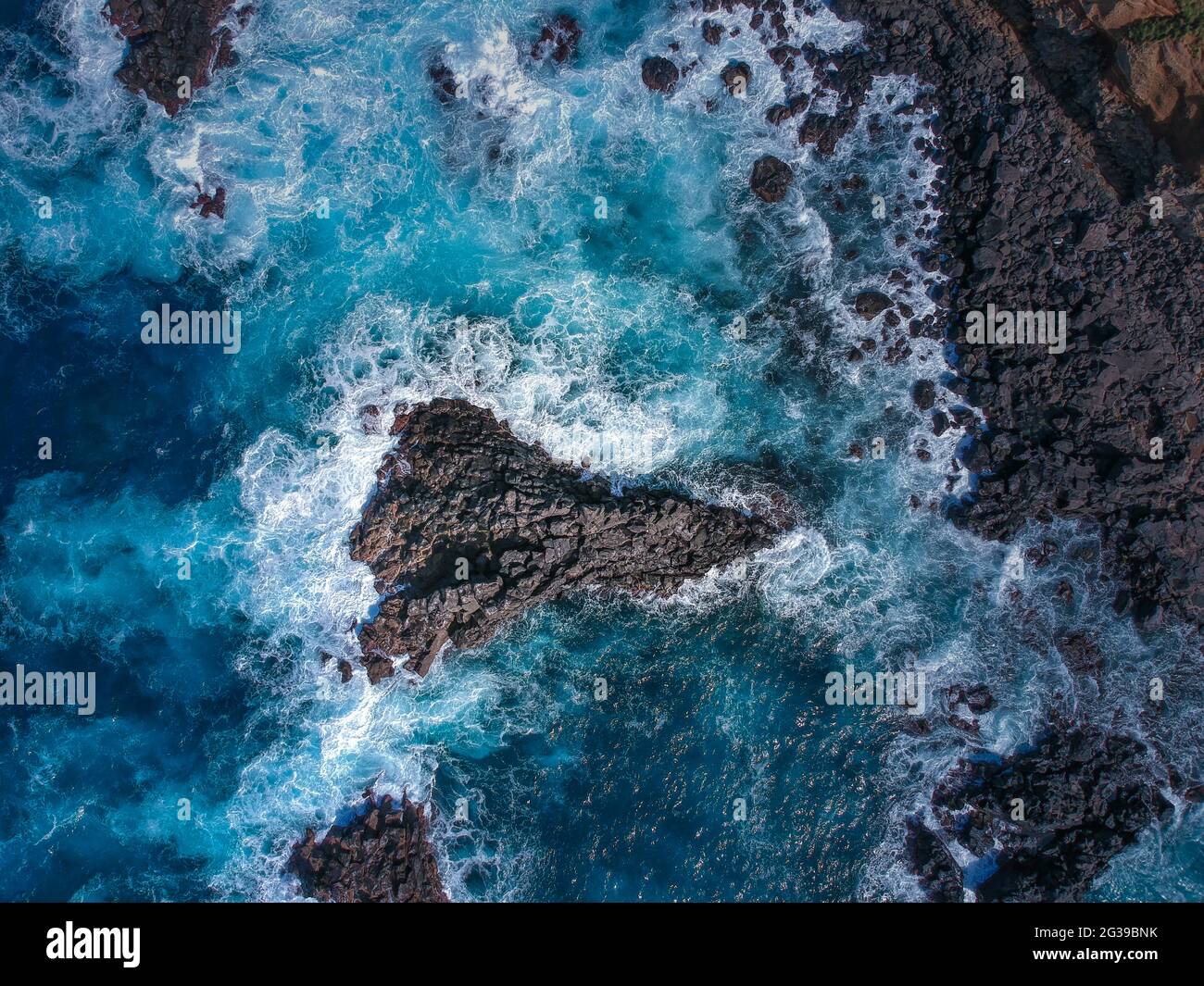 Vue aérienne du dessus des vagues de mer touchant des roches volcaniques noires Banque D'Images