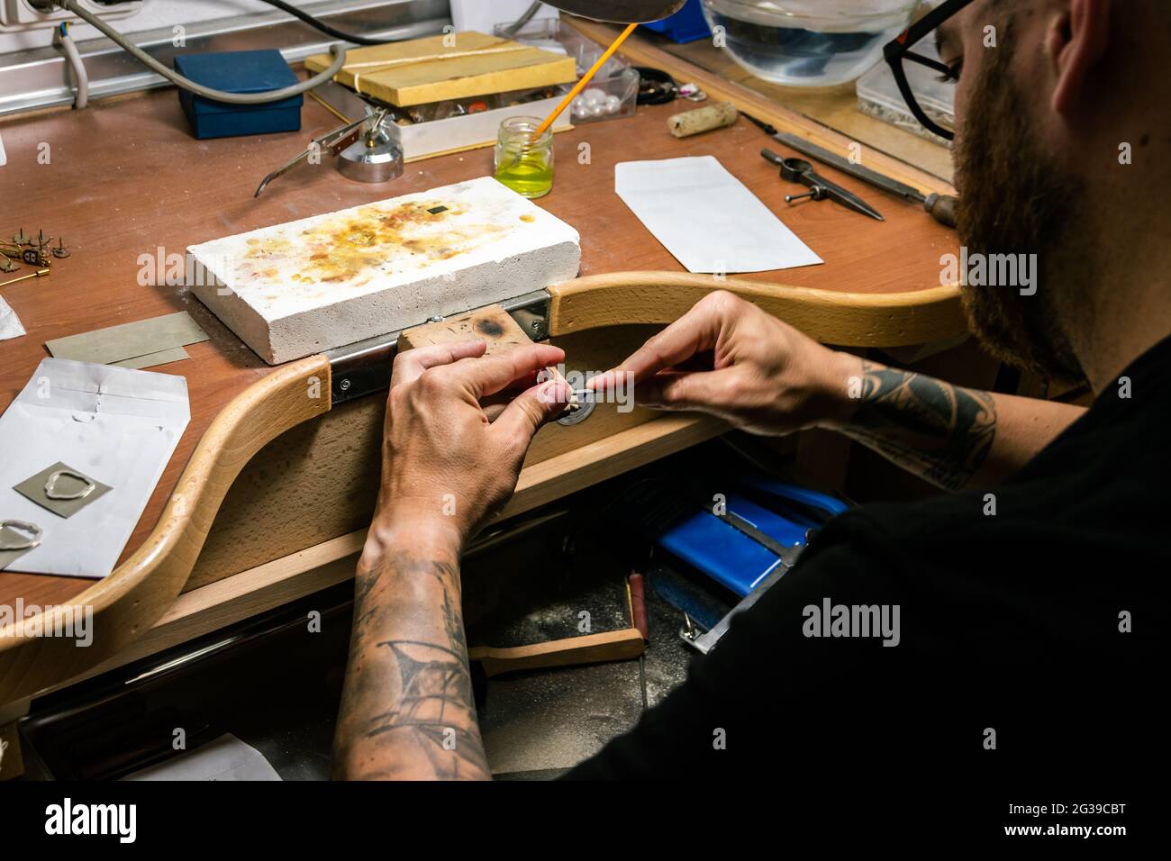 Les mains des hommes dans l'atelier de bijoux de classement d'un morceau d'argent. Plan de détail Banque D'Images