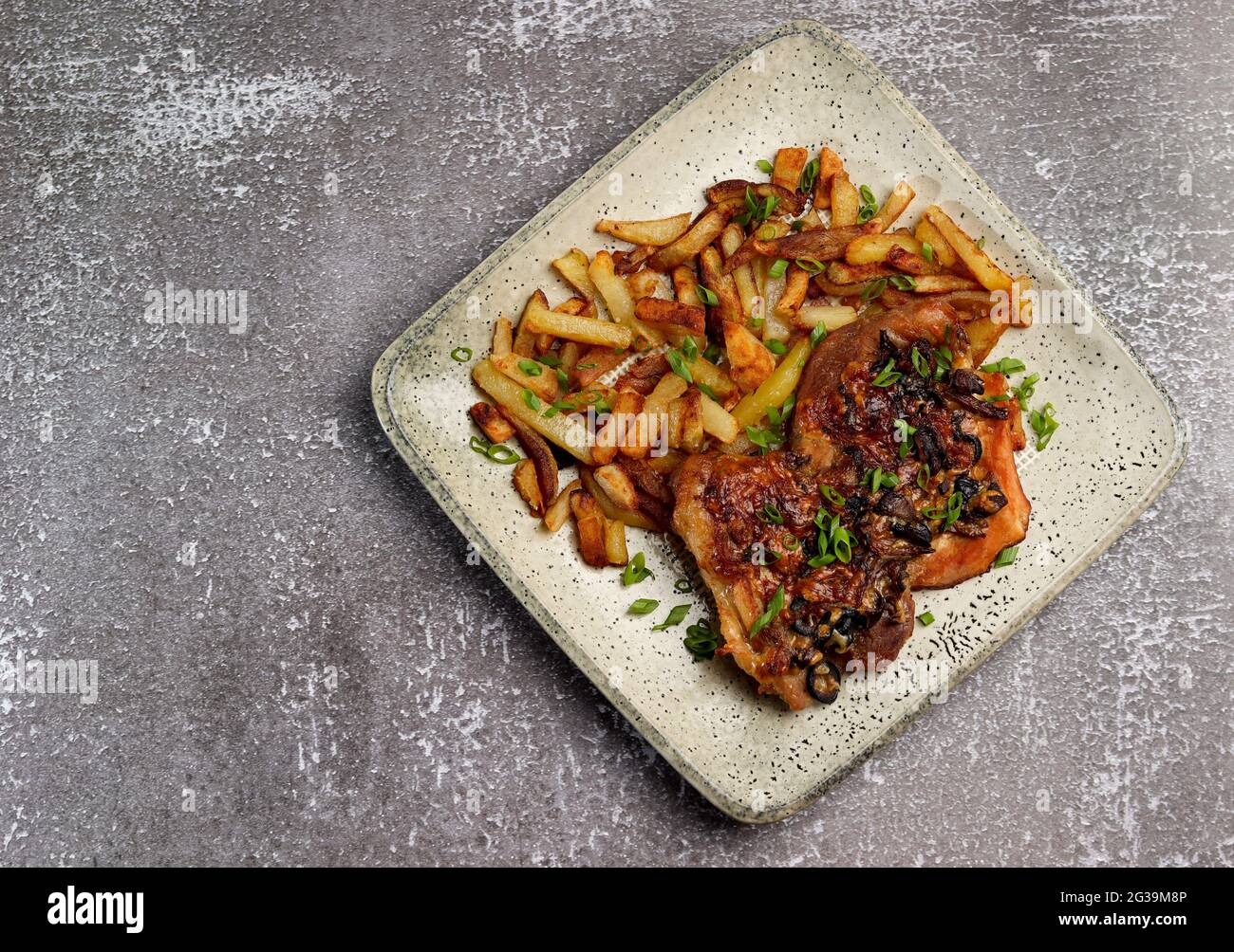 Côtelettes de porc aux champignons servies avec des pommes de terre frites sur une assiette rectangulaire sur fond sombre. Vue de dessus, plan d'appartement Banque D'Images