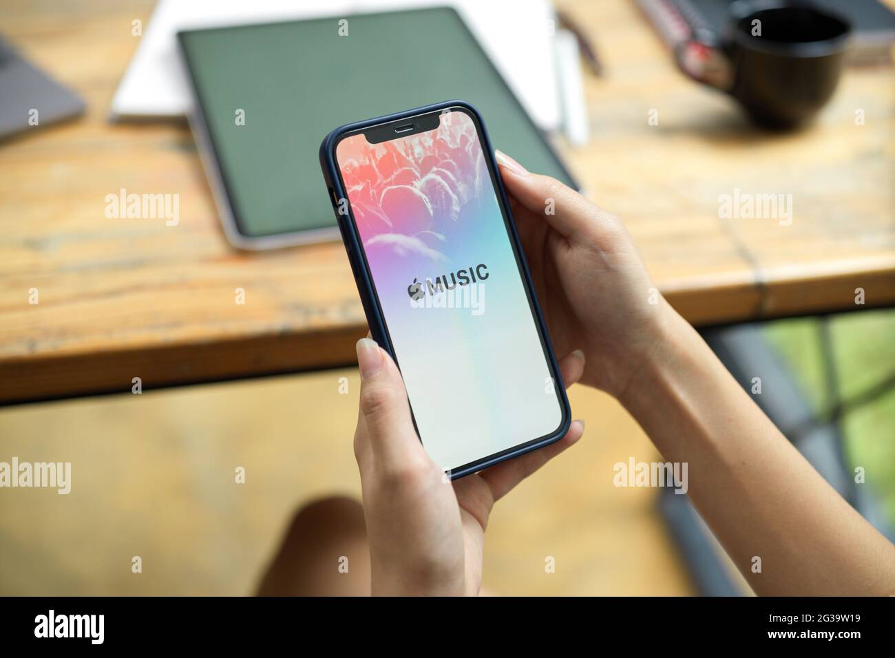 CHIANG MAI,THAÏLANDE - 14 juin 2021 : main féminine tenant l'iPhone avec l'app Apple Music tout en travaillant. Apple Music est la diffusion de musique sur iTunes Banque D'Images