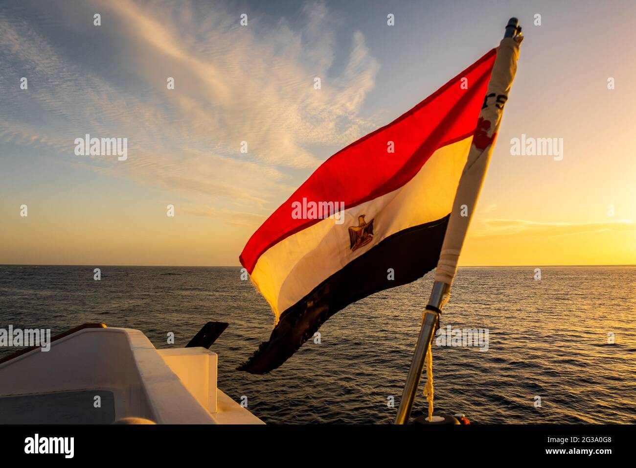 Drapeau de l'Égypte agitant sur un navire avec beau coucher de soleil orange et violet sur la mer Rouge en arrière-plan. Banque D'Images