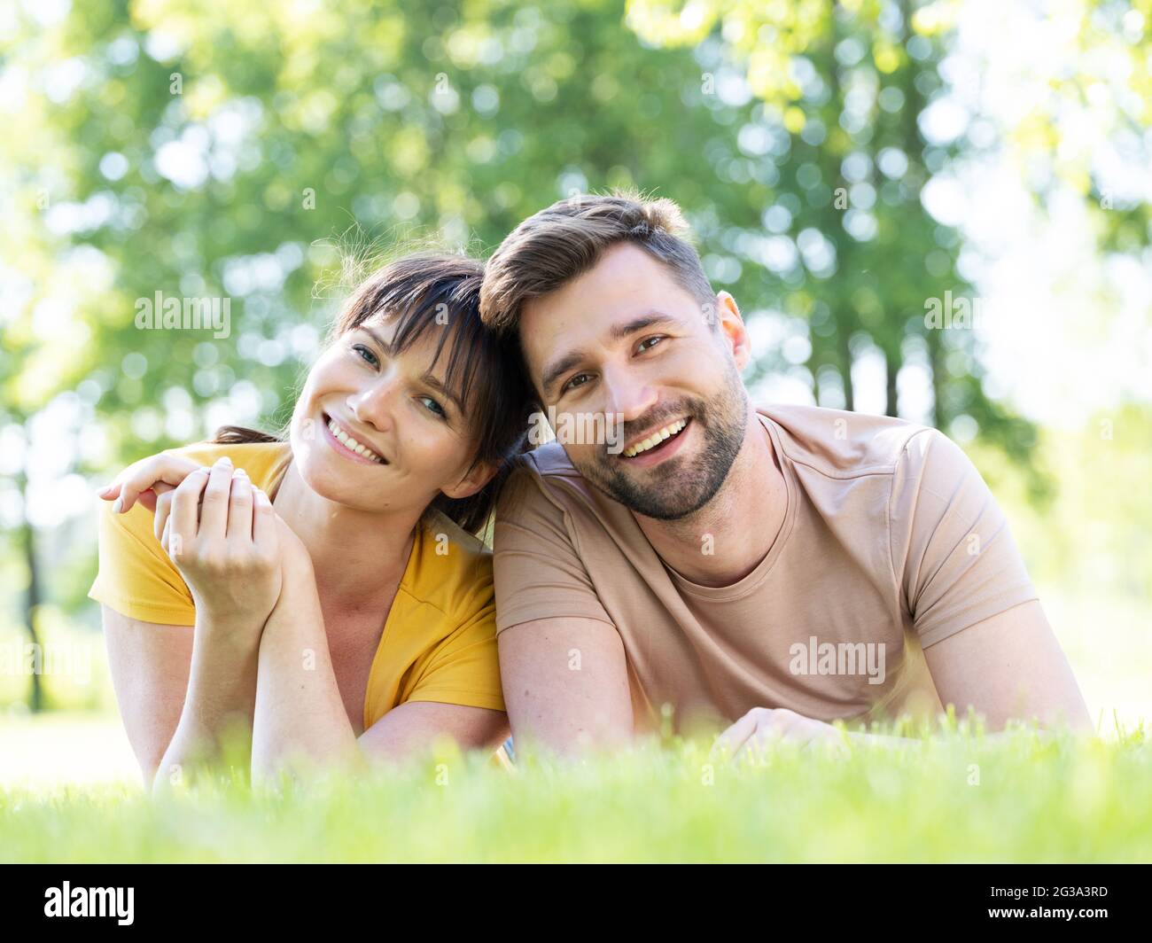 Joyeux couple d'adultes de taille moyenne allongé à l'extérieur sur l'herbe et souriant Banque D'Images