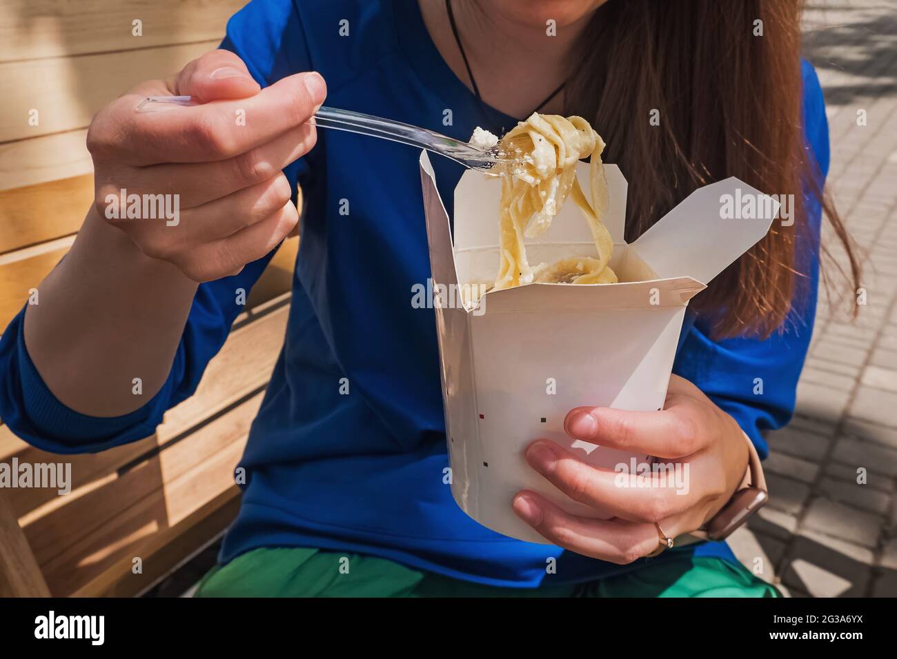 Gros plan de la femme mangeant des pâtes tagliatelles dans une boîte en papier. Banque D'Images