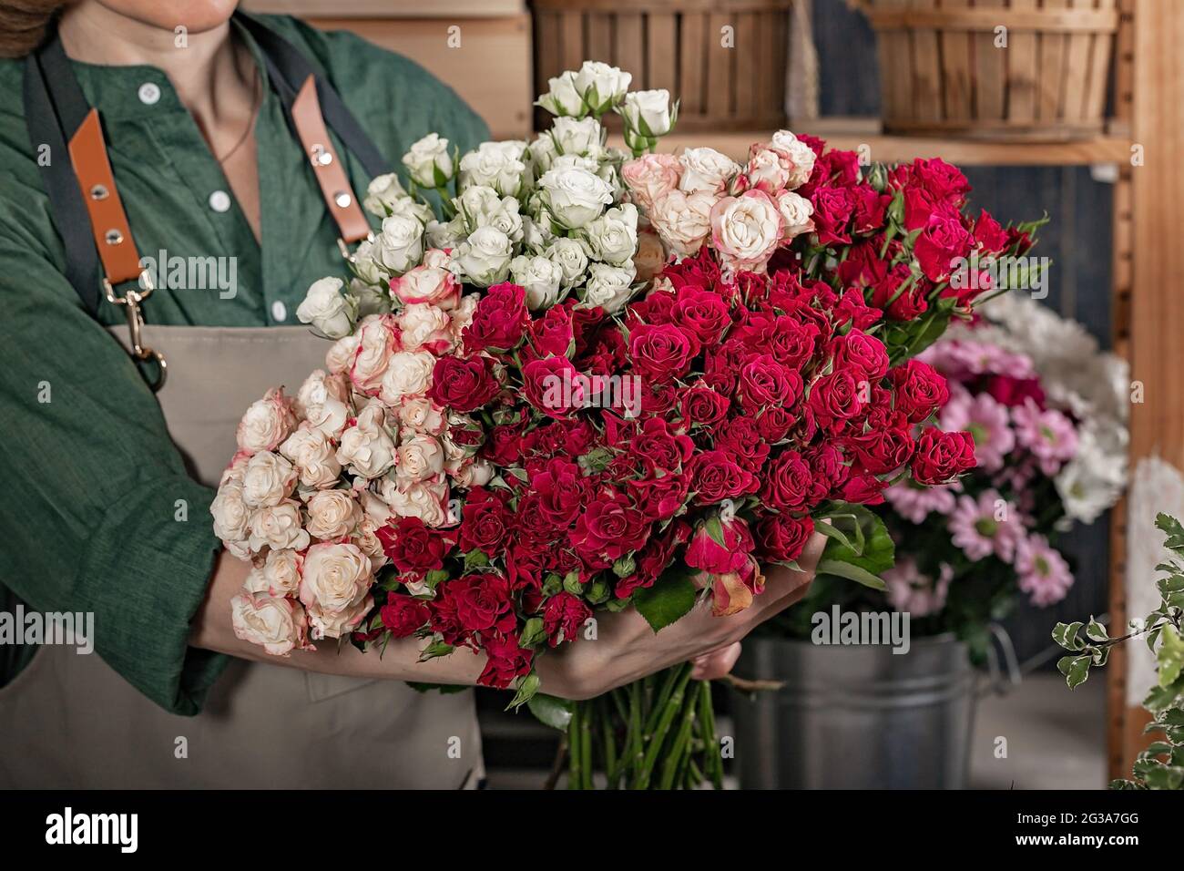 Femme fleuriste tient un grand bouquet de roses. Lieu de travail du fleuriste. Concept de petite entreprise. Boutique de fleurs et d'accessoires. Gros plan Banque D'Images