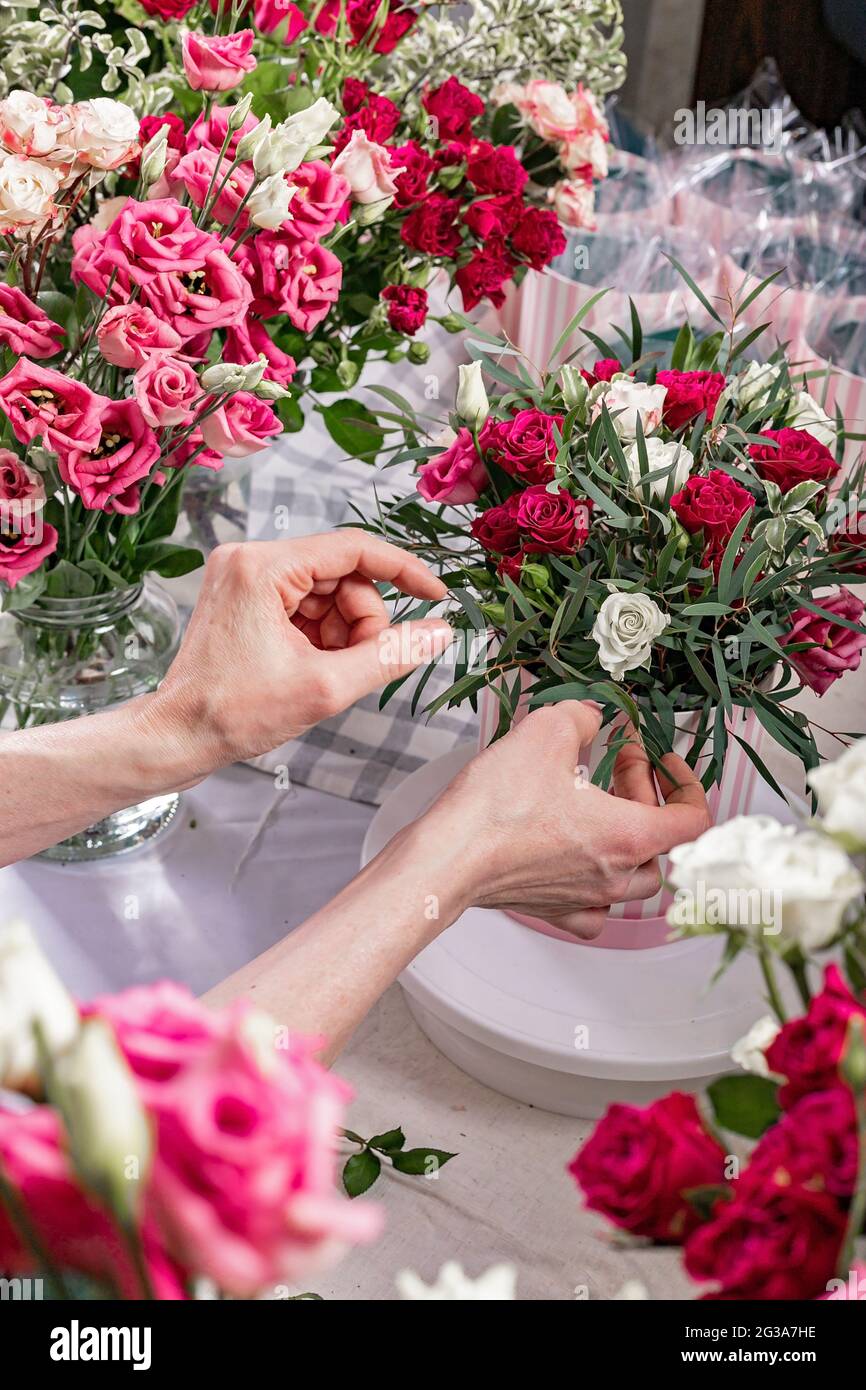 Les mains féminines gracieuses font un beau bouquet. Le fleuriste fait des bouquets cadeaux dans des boîtes à chapeaux. Lieu de travail du fleuriste. Concept de petite entreprise. Vue avant. Fleur Banque D'Images