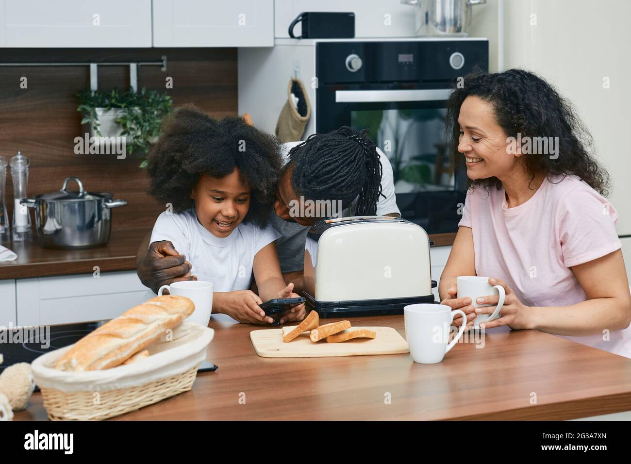 Une famille positive avec un enfant passe du temps ensemble dans une cuisine tout en cuisinant Banque D'Images