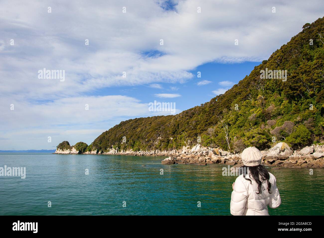 La jeune femme admire le paysage. Vue arrière, fille en blouson blanc regardant l'île d'Adele (Motuareronui), populaire auprès des kayakistes et des pêcheurs Banque D'Images