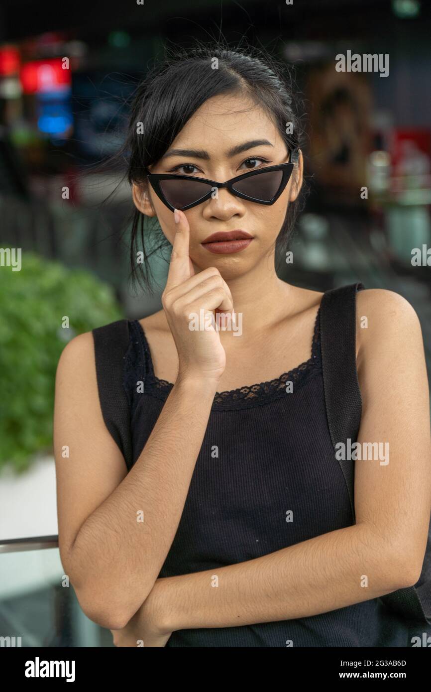 Sexy asiatique fille dans la rue noir vêtements jeans avec sac à dos lunettes de soleil Banque D'Images