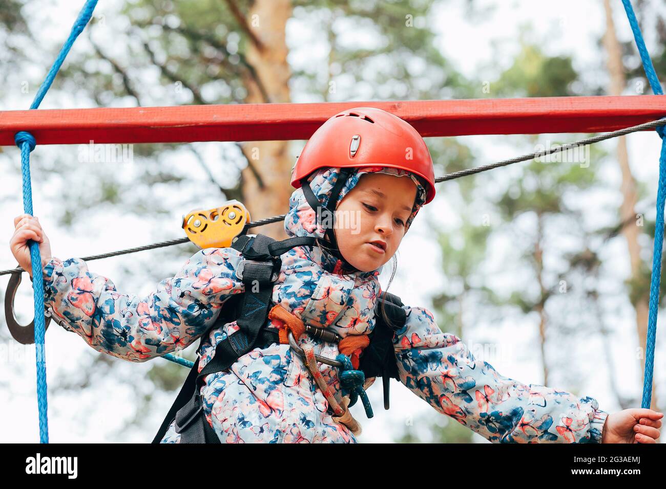 Petite fille de 7 ans marcher sur un pont de corde de la ville dans le parc de corde d'aventure. Loisirs pour les enfants Banque D'Images