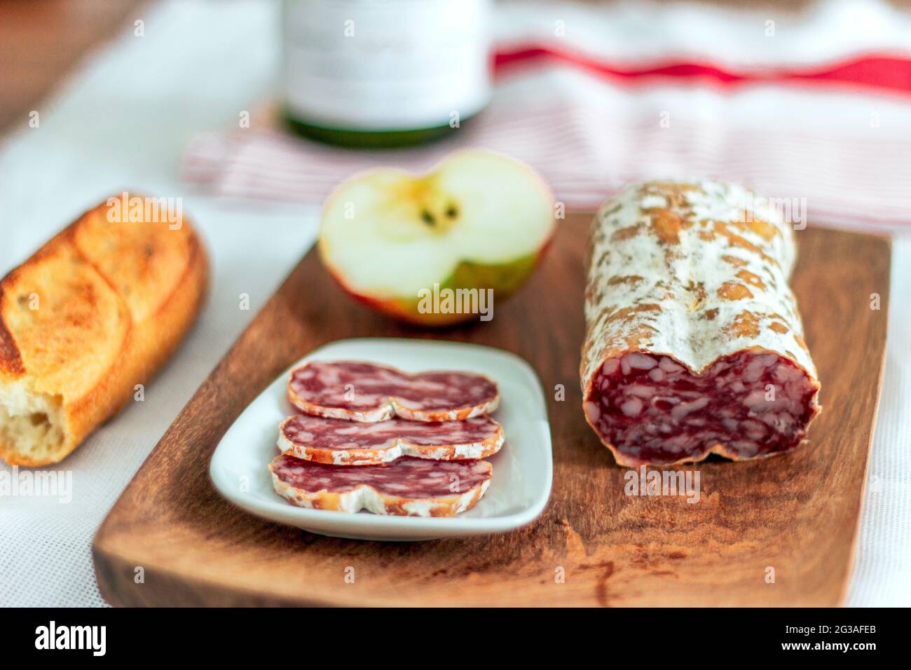 Assiette de viande séchée avec salami, pain croustillant à la baguette, pomme et vin sur une planche en bois Banque D'Images