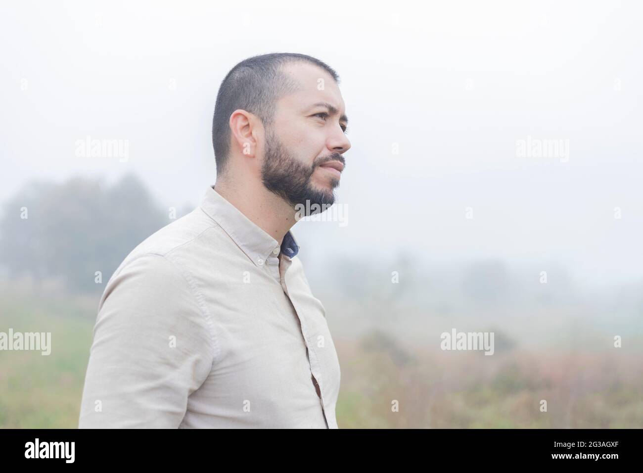 latino barbu debout dans la ferme par une journée nuageux Banque D'Images