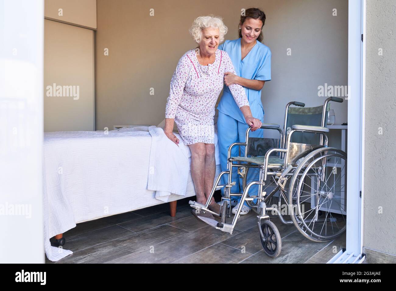 Une infirmière âgée aide les personnes âgées du lit au fauteuil roulant à  l'hôpital Photo Stock - Alamy