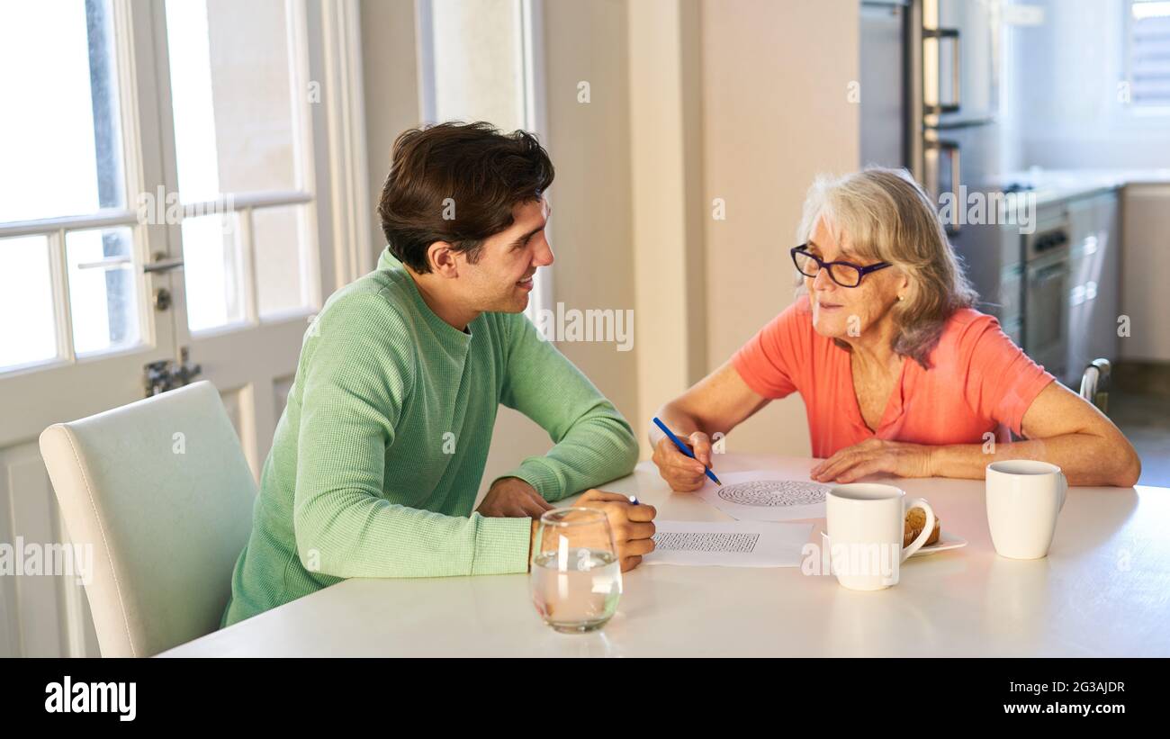 L'homme résout les teasers de cerveau avec une femme âgée démante à la table à la maison Banque D'Images