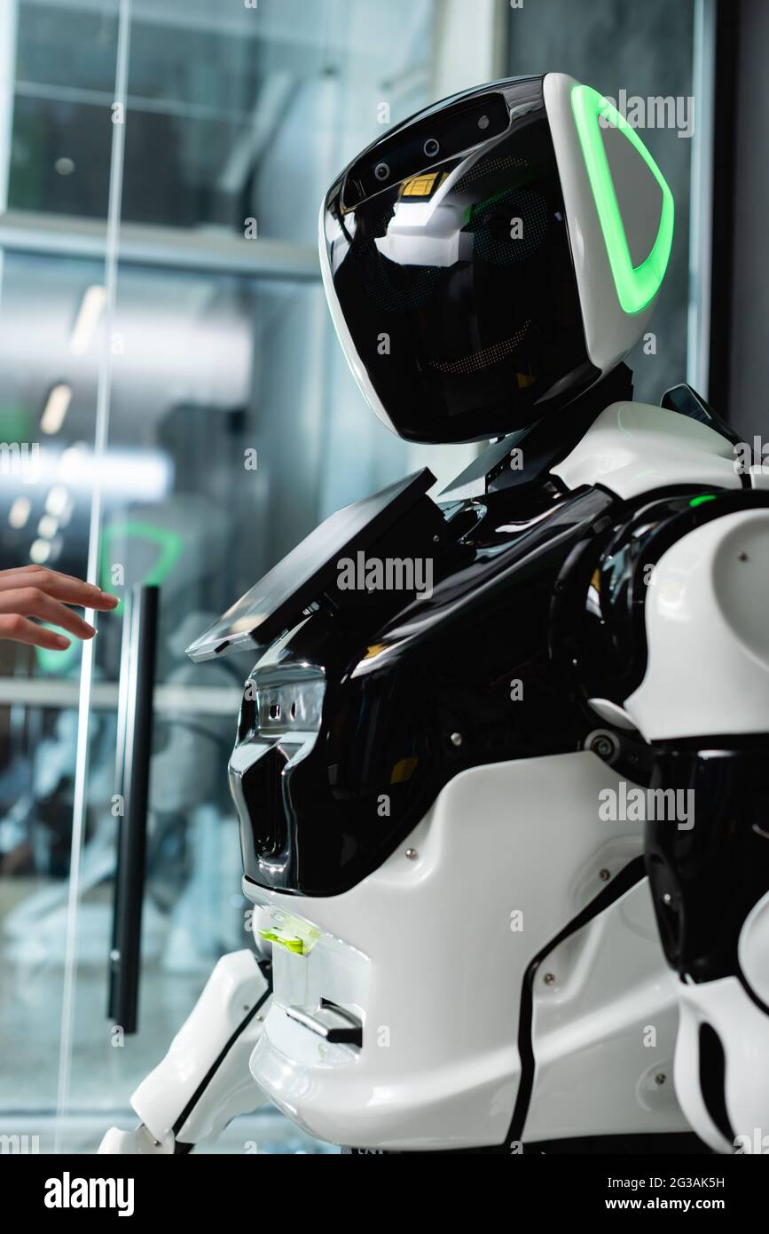 vue rognée de la main féminine près du robot humanoïde dans le bureau Banque D'Images